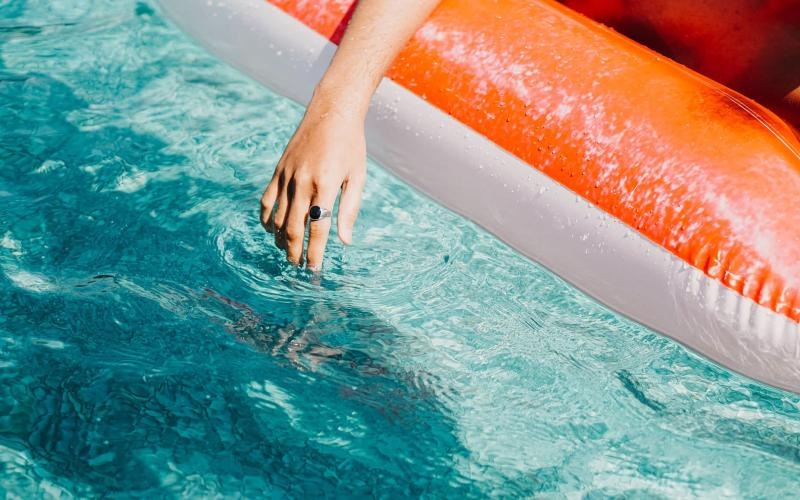 woman dangles her hand in the pool as she floats in an inflatable vessel